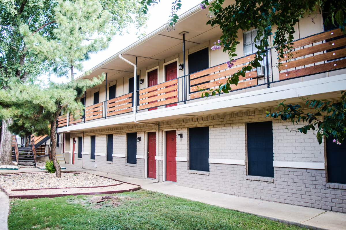 the exterior of an apartment building with a green lawn at The Cedars Apartments