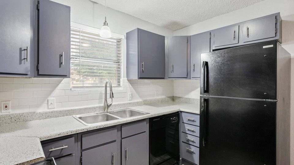 a kitchen with black appliances and gray cabinets at The Breezeway Townhomes