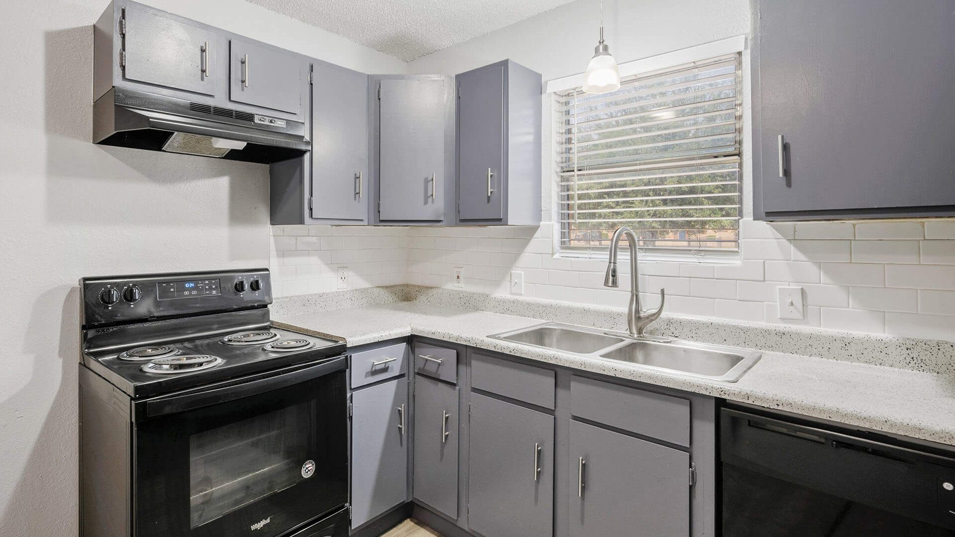 a kitchen with black appliances and gray cabinets at The Breezeway Townhomes