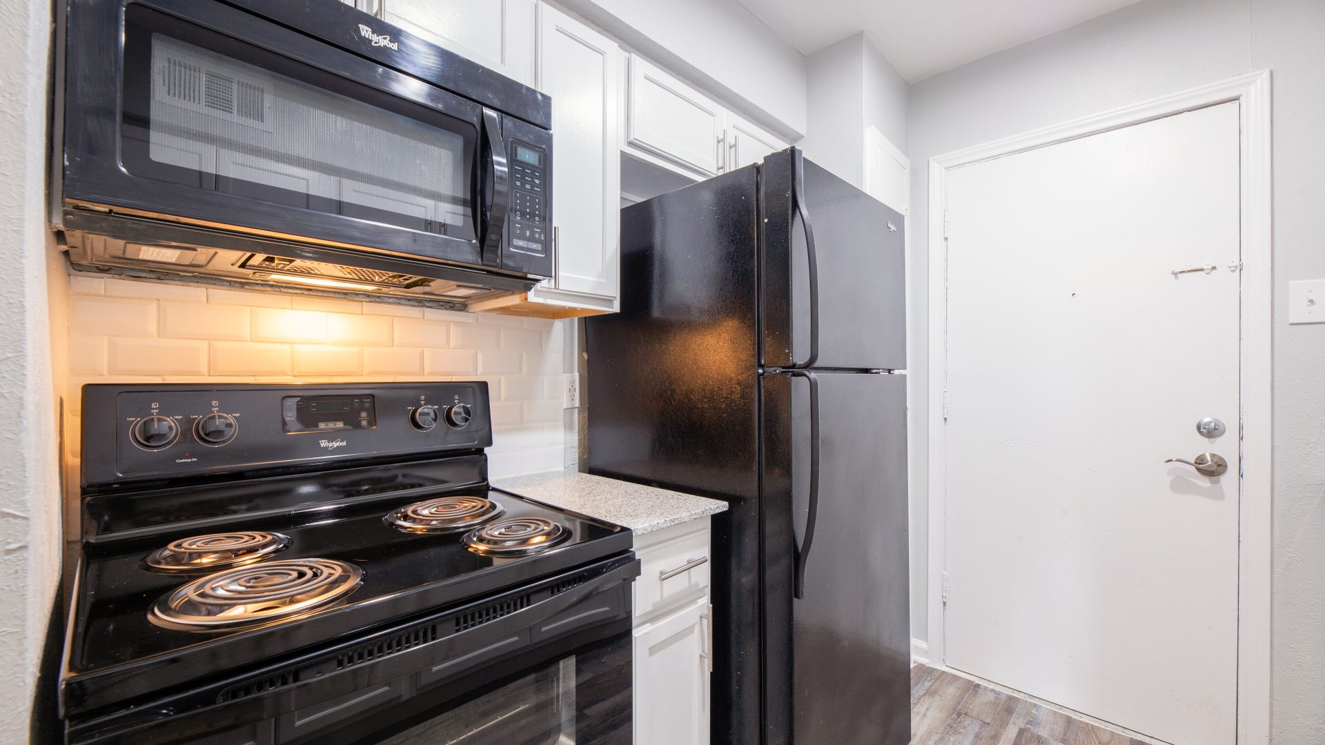 kitchen with black stove micro fridge white cabinets