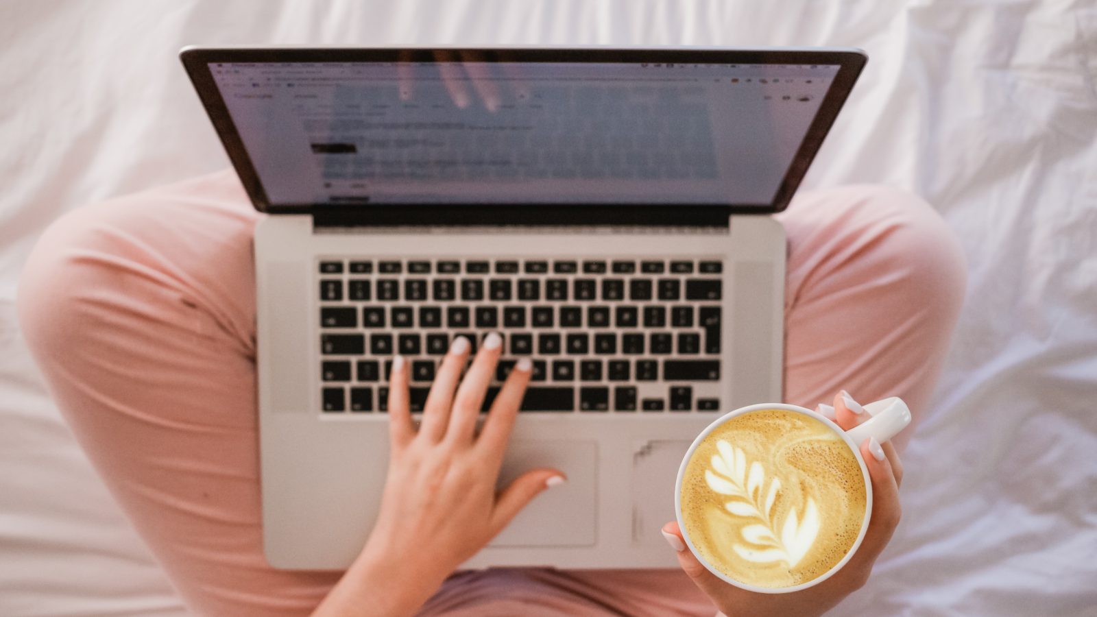 person using MacBook Pro and holding cappuccino