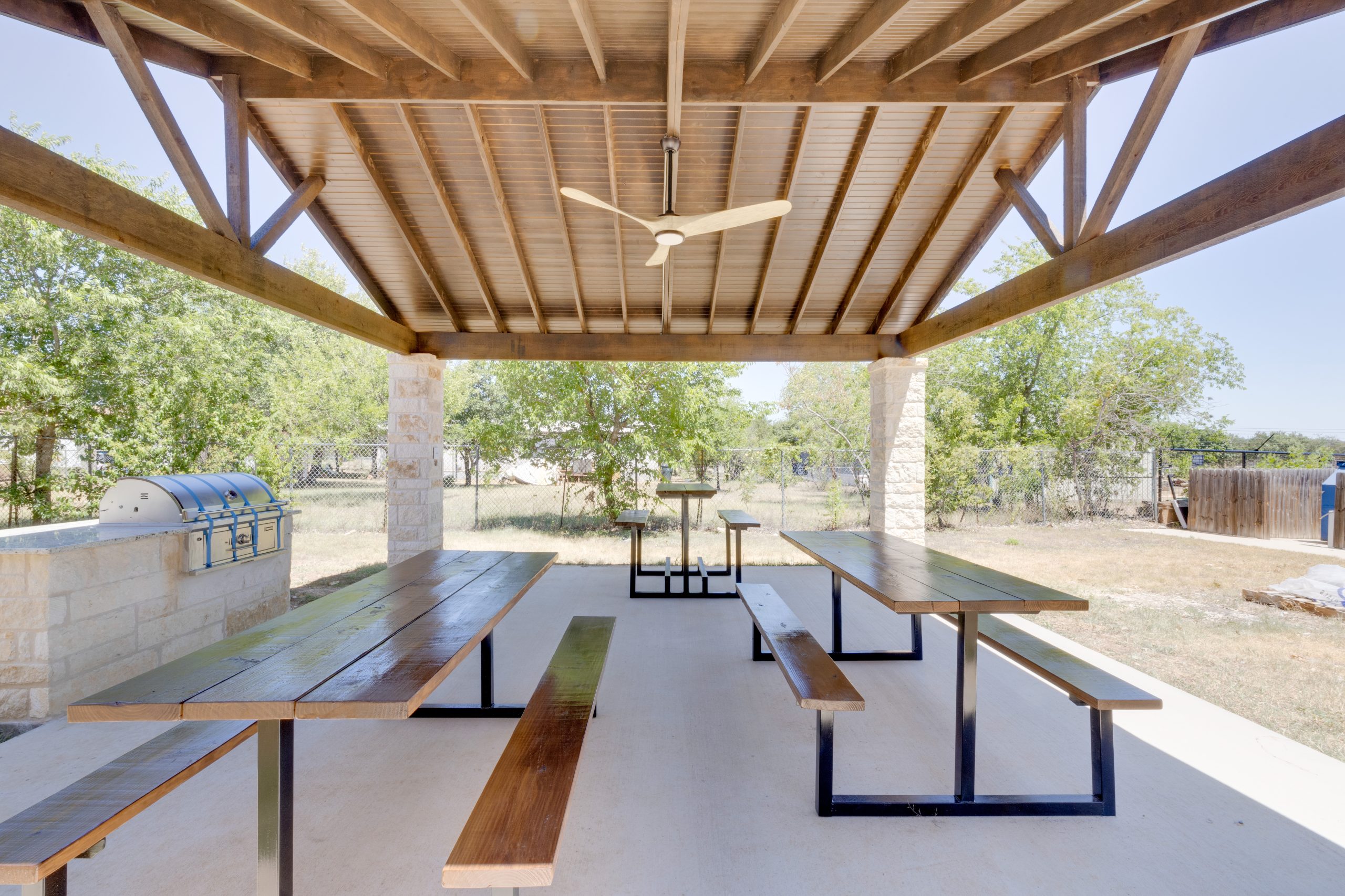 a covered picnic area with benches and tables at The Blanco Oaks Apartments