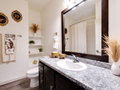 One-Bedroom Apartments in Boerne, TX - Garden Creek Apartments - Bathroom with Built-In Shelves, Garden-Style Tub with Tiled Walls, and a Large Vanity