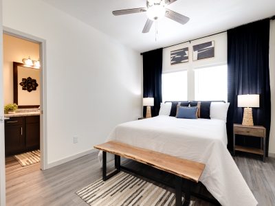 a bedroom with a bed, a nightstand and a ceiling fan at The Garden Creek Apartments