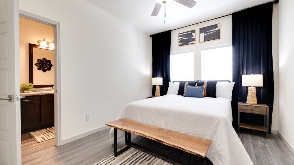 a bedroom with a bed, a nightstand and a ceiling fan at The Garden Creek Apartments