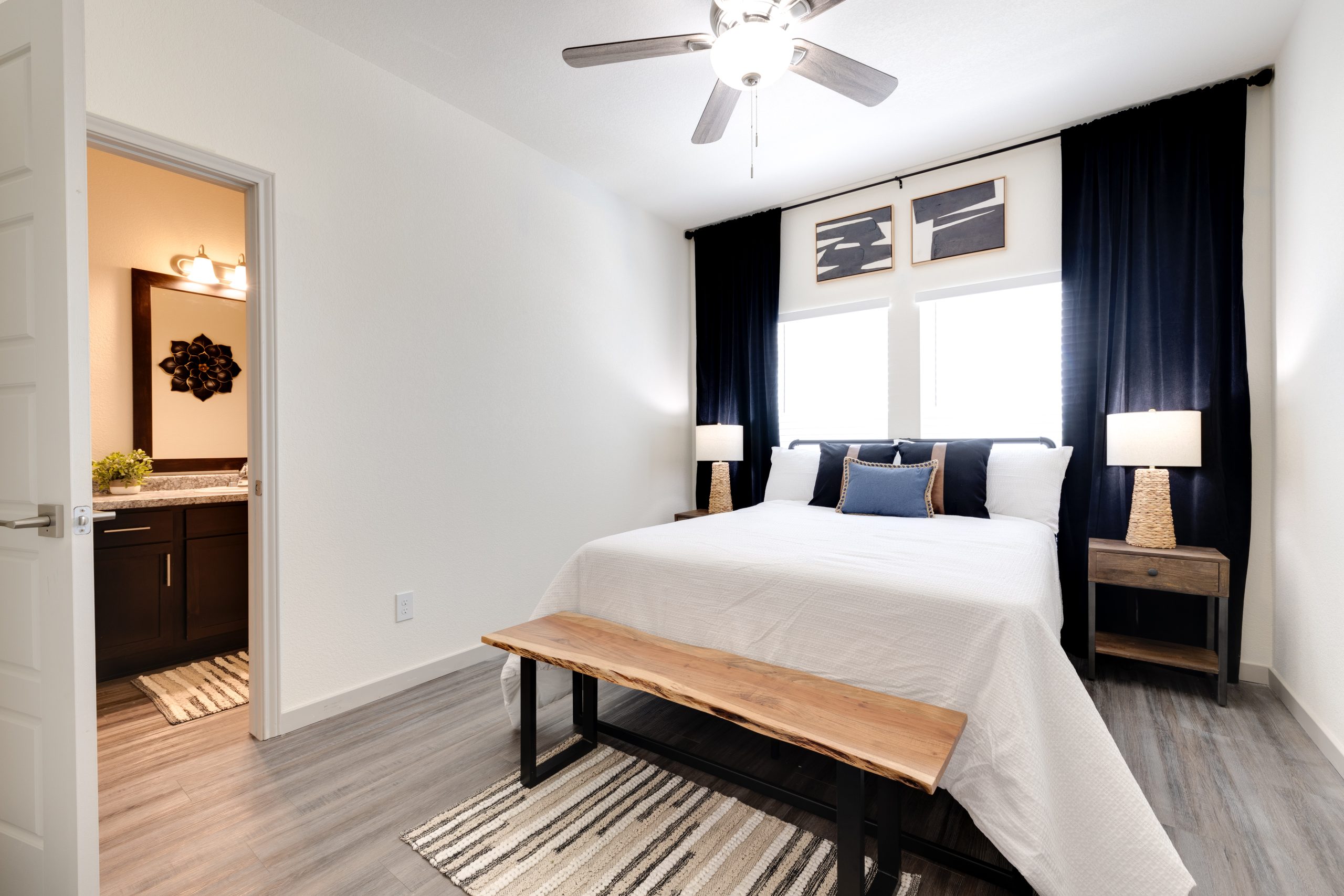 a bedroom with a bed, a nightstand and a ceiling fan at The Garden Creek Apartments