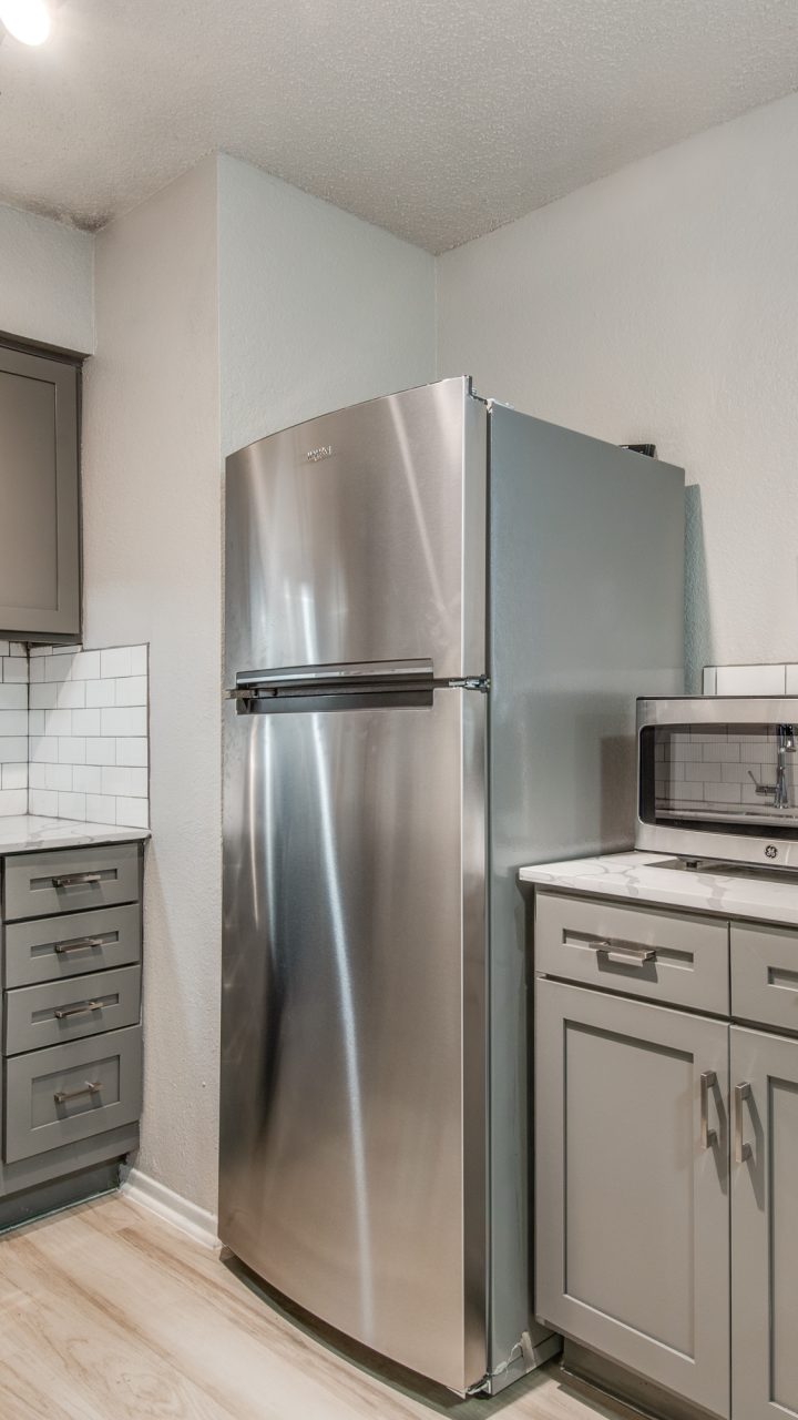 a kitchen with stainless steel appliances and gray cabinets at The 8500 Harwood