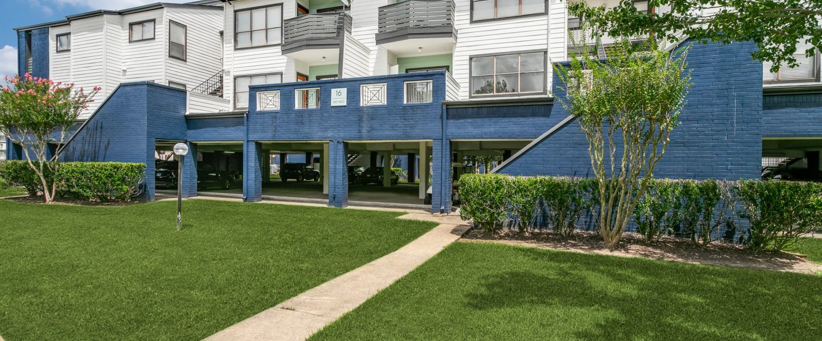 the front of an apartment building with grass and trees at The Pearce on  Lake