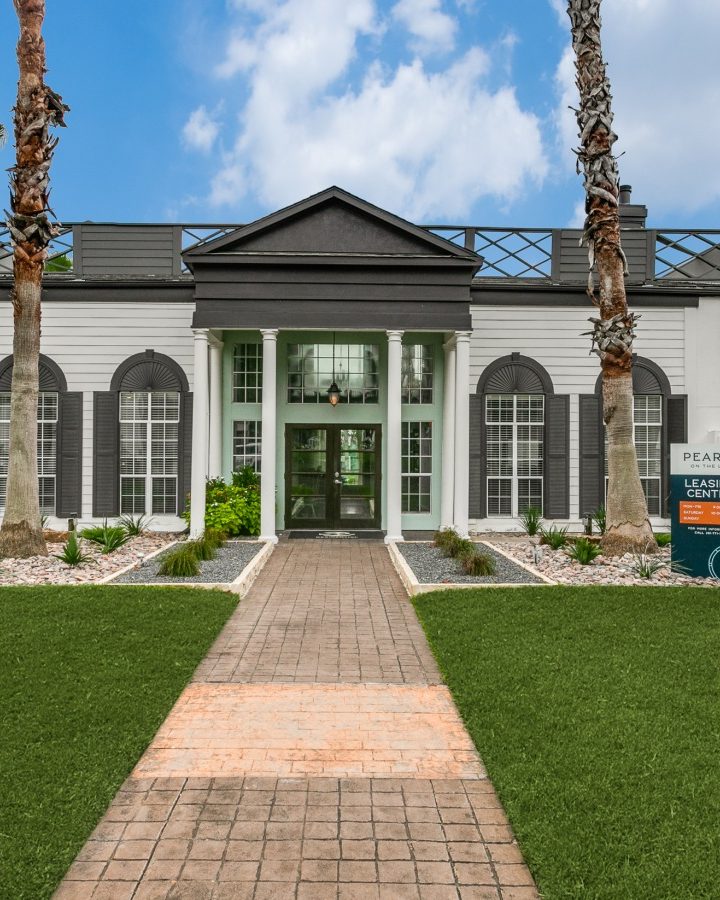 the front entrance to a building with palm trees and grass at The Pearce on  Lake