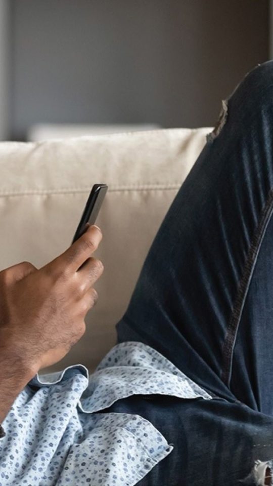 a man sitting on a couch with his feet up and his phone in his hand at The Richmond