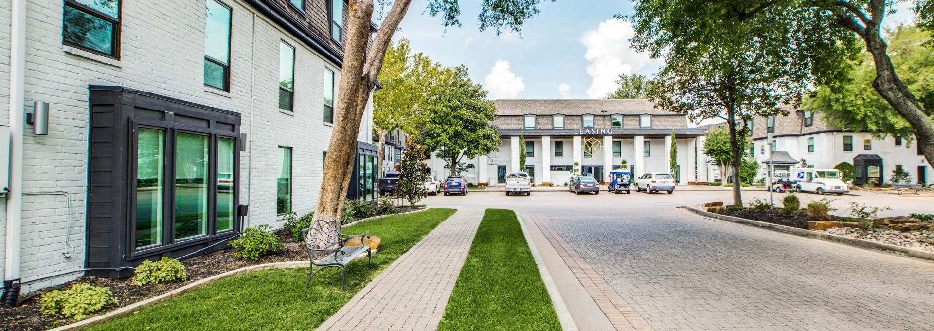 a street with grass and trees in front of a building at The WESTON