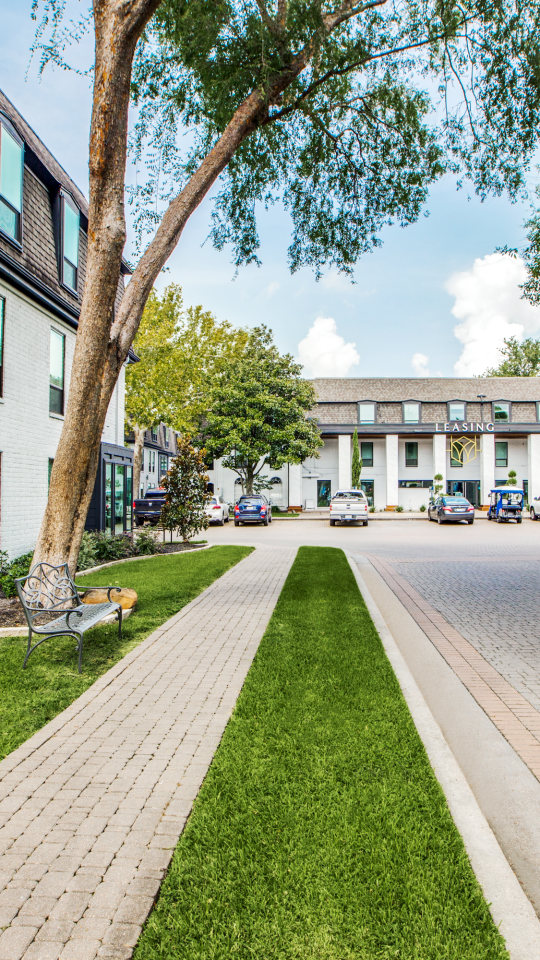 a street with grass and trees in front of a building at The WESTON