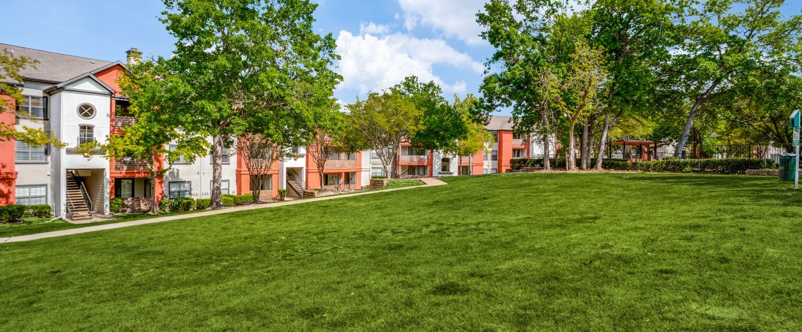 the green grass and trees in front of the apartment complex at The  Lana