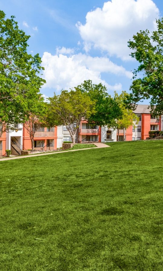 the green grass and trees in front of the apartment complex at The  Lana