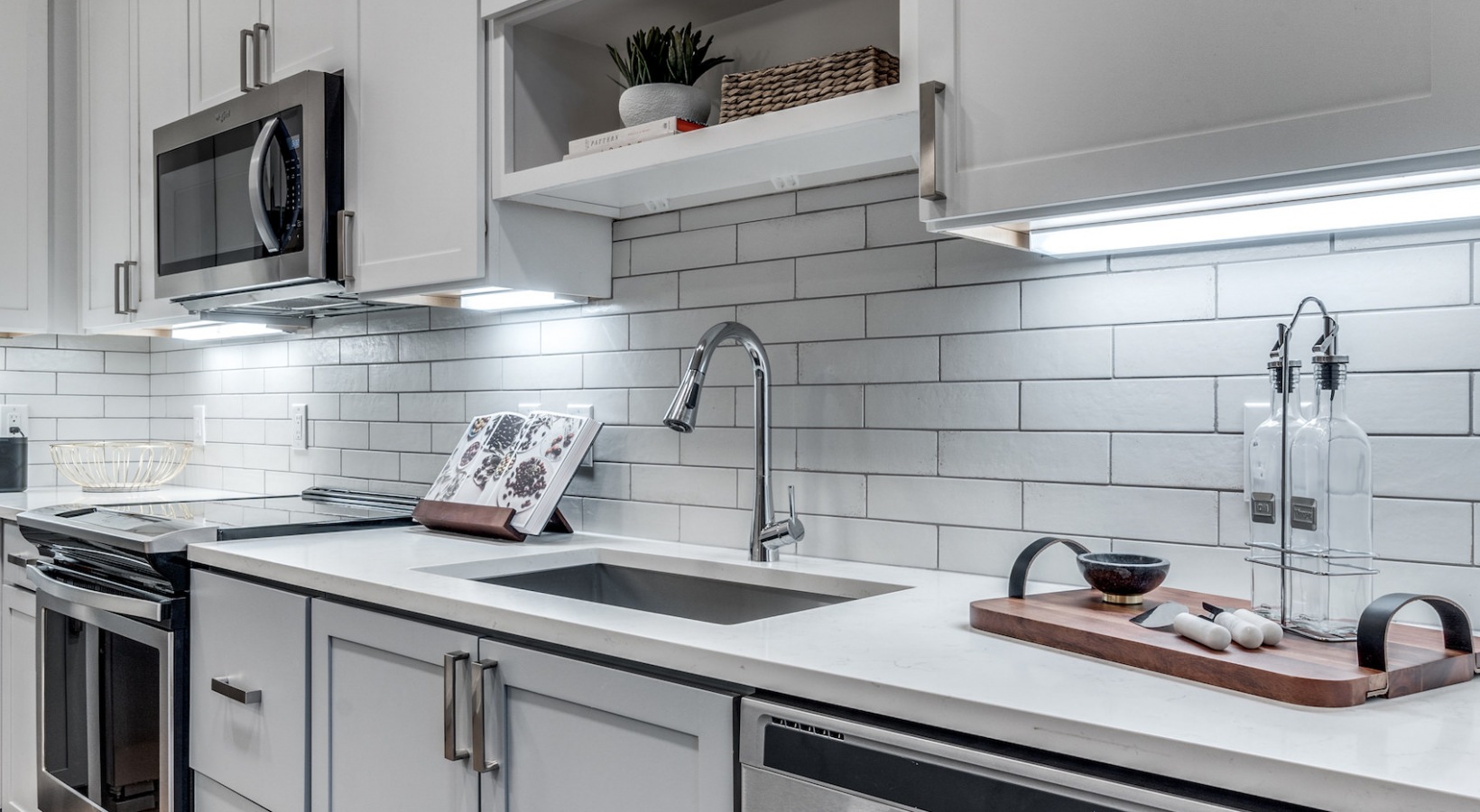 a kitchen with white cabinets and stainless steel appliances at The Cedar at  Branch
