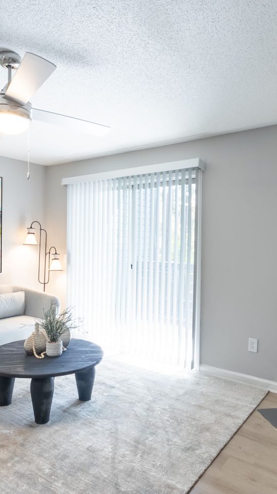 a living room with a fireplace and a ceiling fan at The  Jaxon
