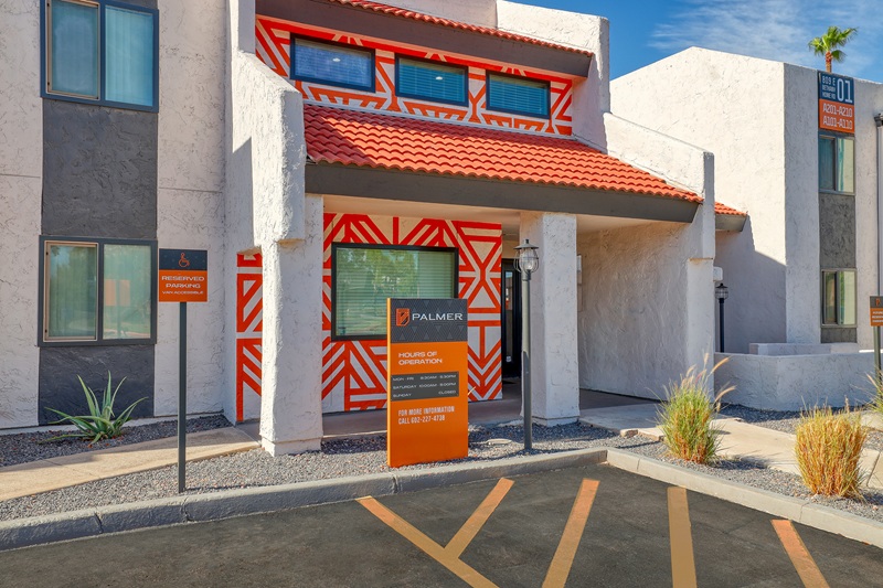 the exterior of an apartment building with a red and orange sign at The  Palmer