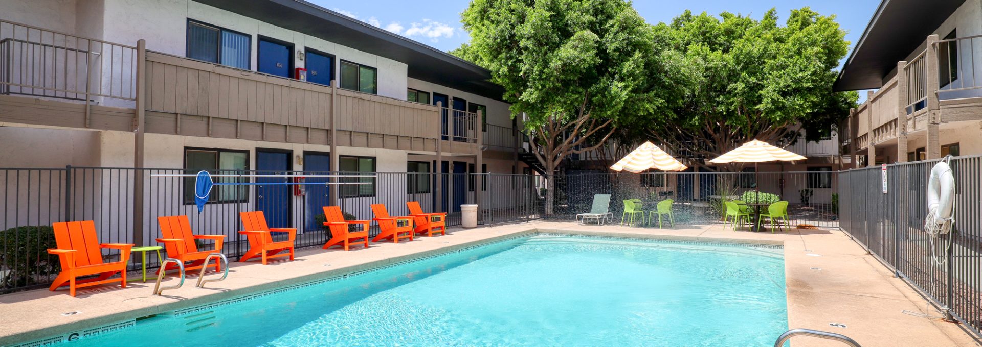 a pool with lounge chairs and umbrellas in front of an apartment building at The  Palmer