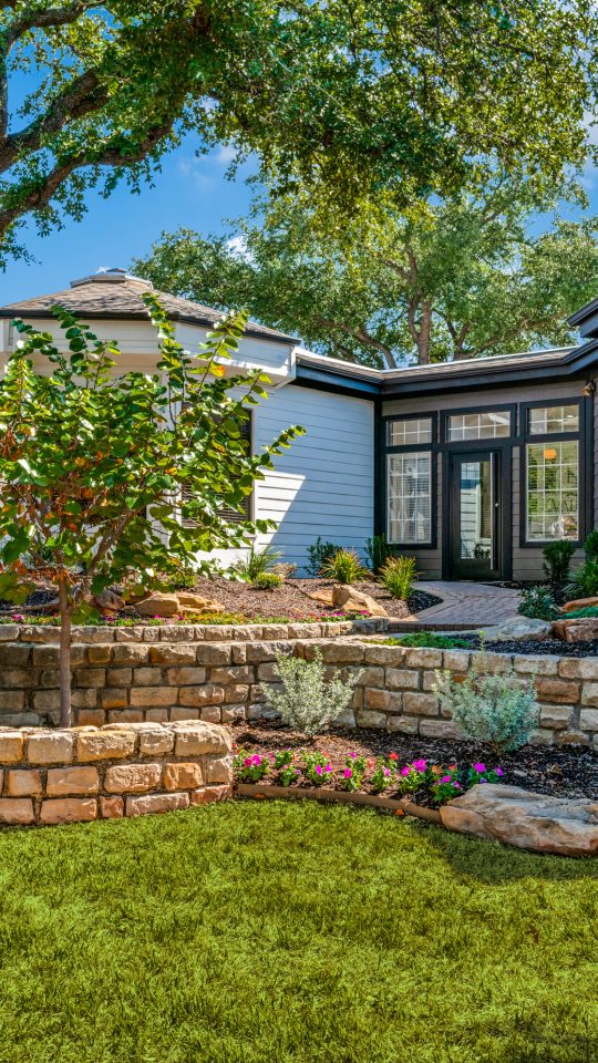 a home with landscaping and a stone wall at The Evaline