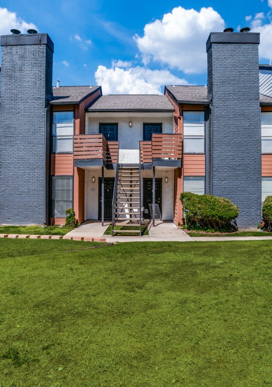 the exterior of an apartment complex with grass and trees at The Evaline