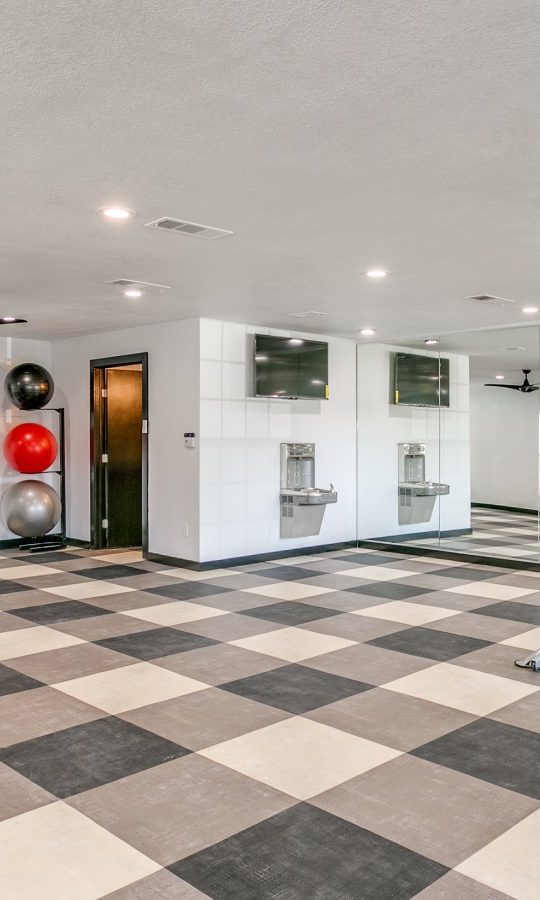 a gym room with a tiled floor and a black and white checkered floor at The  Holden