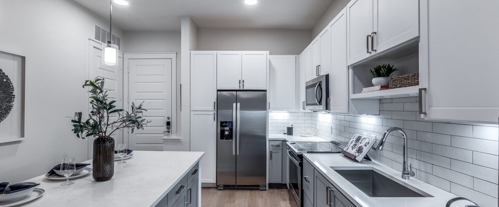 a clean kitchen with stainless steel appliances and white cabinets at The Teak at  Branch