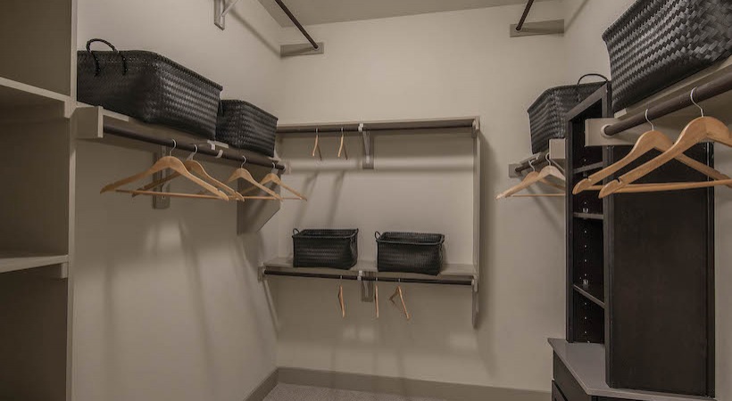 a walk in closet with clothes hanging on the shelves at The Teak at  Branch