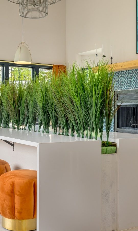 a living room with orange plants and a fireplace at The  Tatum