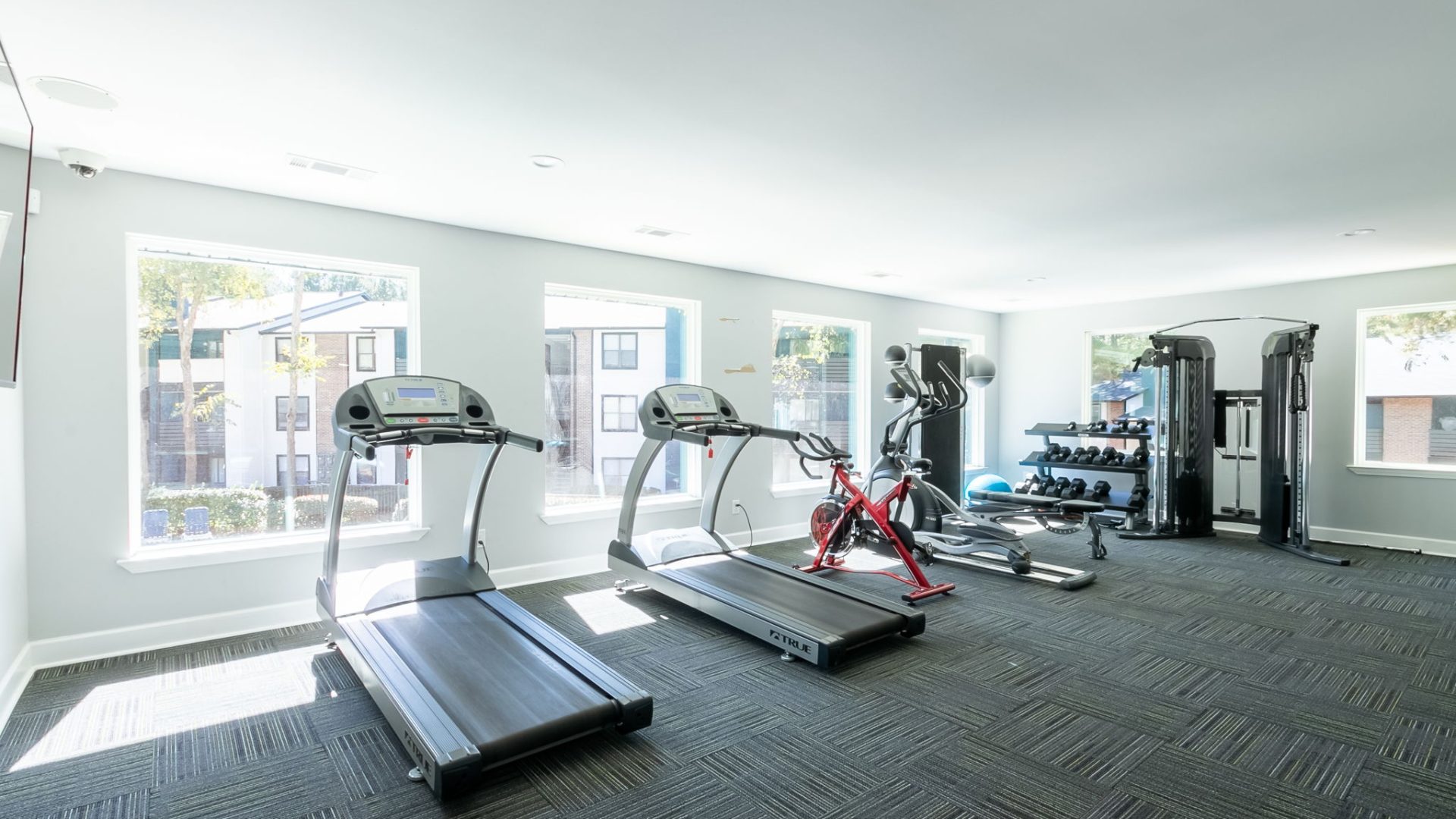 a gym room with tread machines and windows at The  Rowen