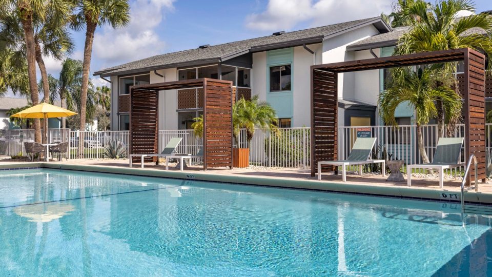 a pool with lounge chairs and umbrellas in front of a building at The Marino