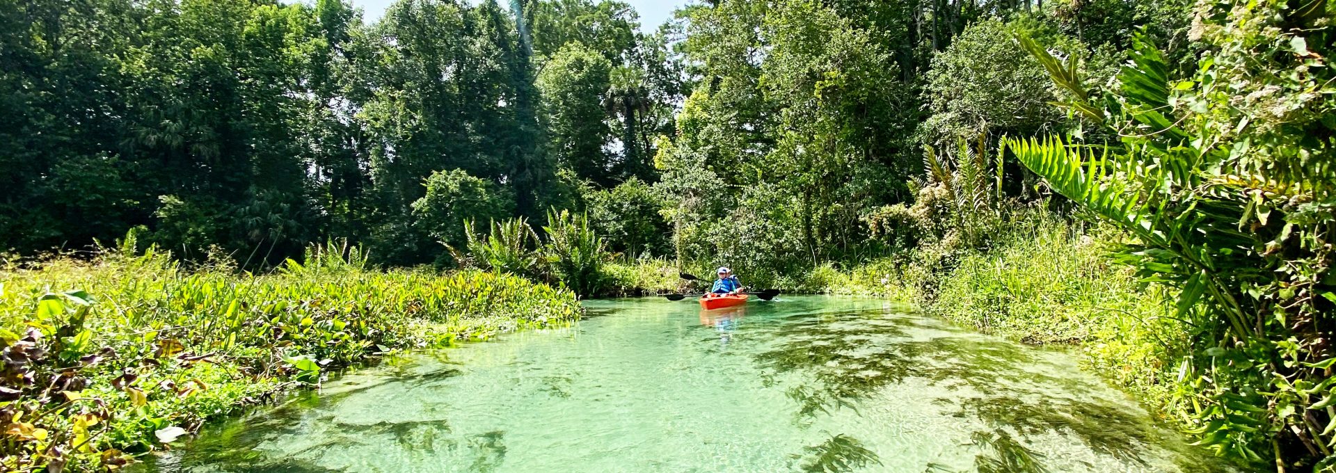 people riding red kayak on river during daytime