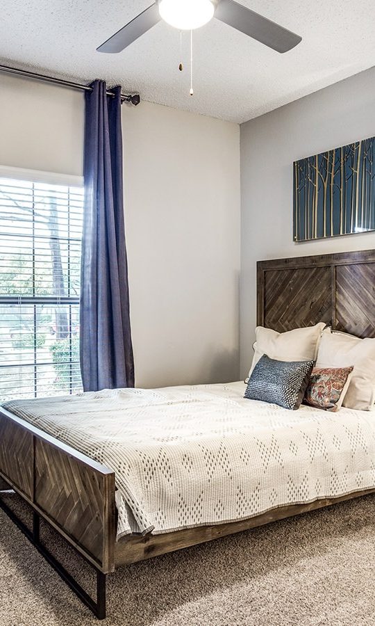 a bedroom with a bed, dresser and ceiling fan at The Hyde Park at Valley Ranch