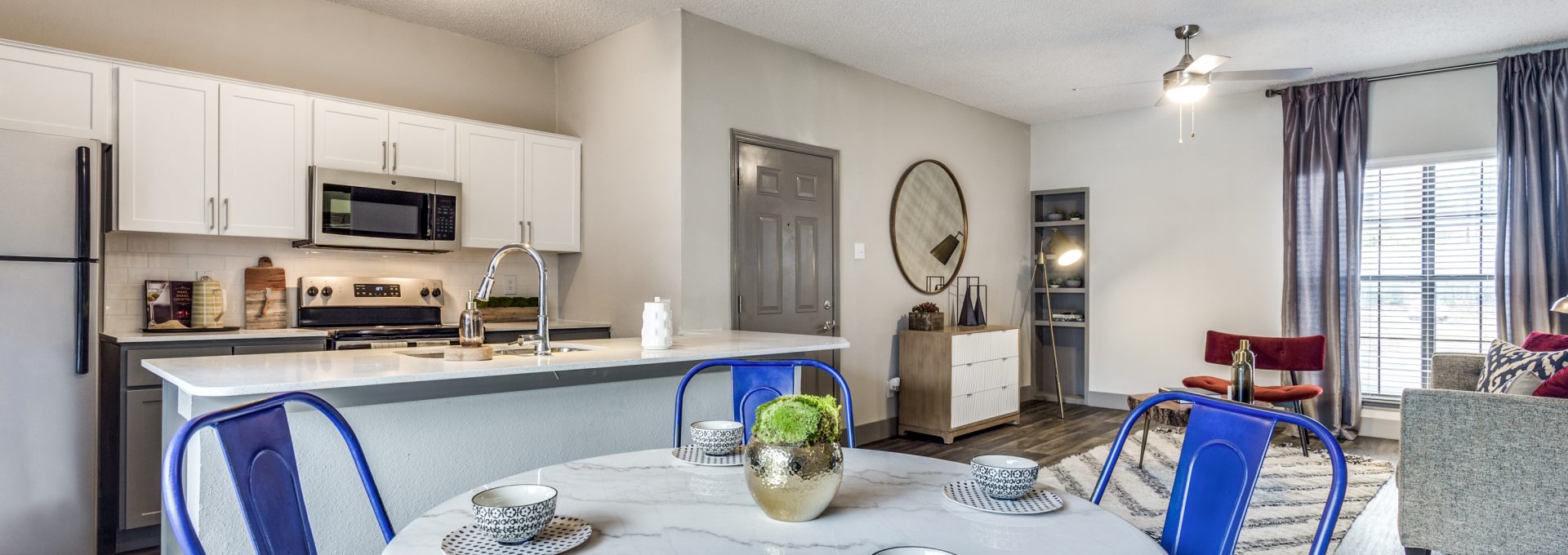 a kitchen and dining room with blue chairs at The Hyde Park at Valley Ranch