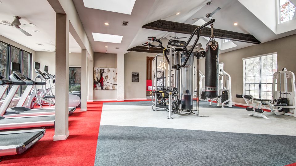 a gym room with tread machines and red carpet at The Hyde Park at Valley Ranch