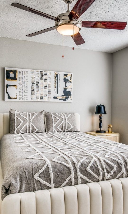 a bedroom with a ceiling fan and white bed at The  Durham