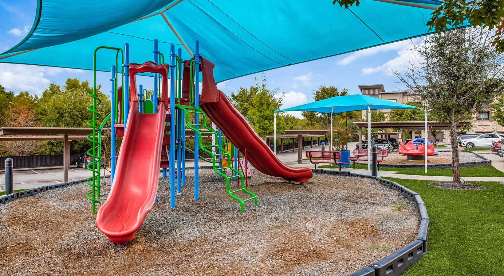 a playground with a blue canopy and slides at The Twin Creeks Crossing