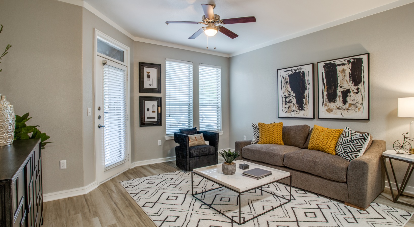 a living room with a ceiling fan and a rug at The Franklin at Samuels Ave