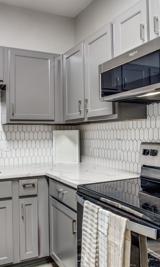 a kitchen with stainless steel appliances and white cabinets at The  Franklin at Samuels Ave