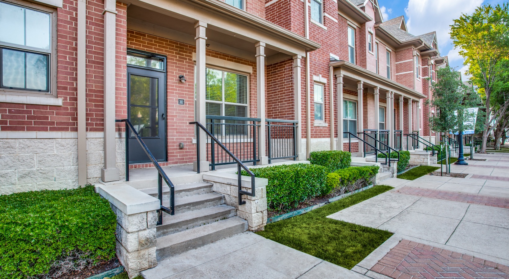 a brick walkway with steps leading to a front door at The Franklin at Samuels Ave