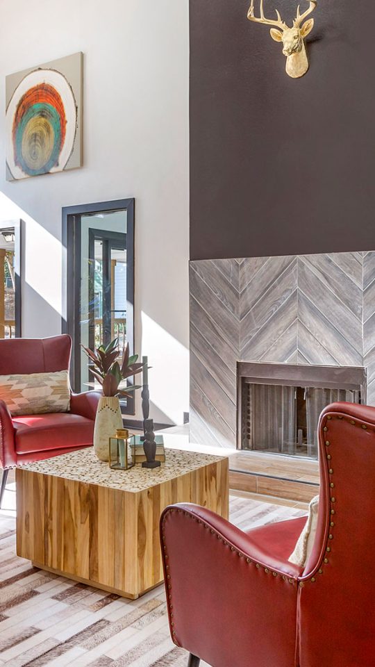 a living room with red chairs and a fireplace at The  Breck