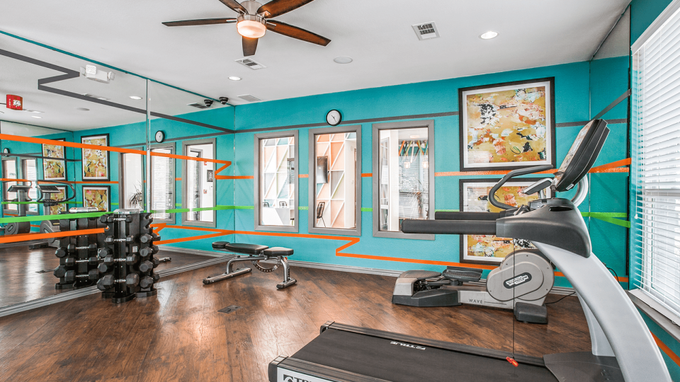 a gym room with a treadmill, exercise bike and mirrors at The Zeke