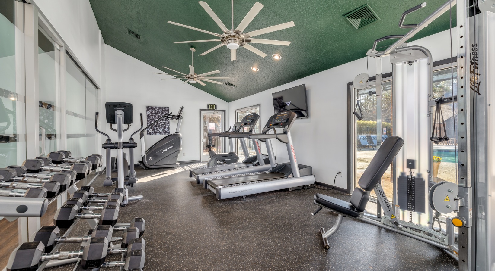 a gym room with exercise equipment and ceiling fans at The Quinn on Ravenglass