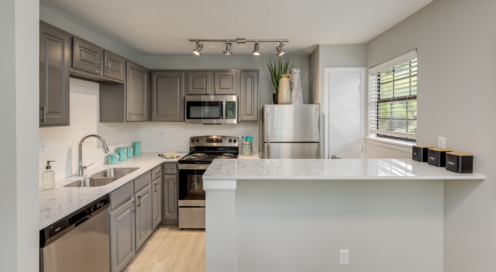 a kitchen with stainless steel appliances and gray cabinets at The Quinn on Ravenglass