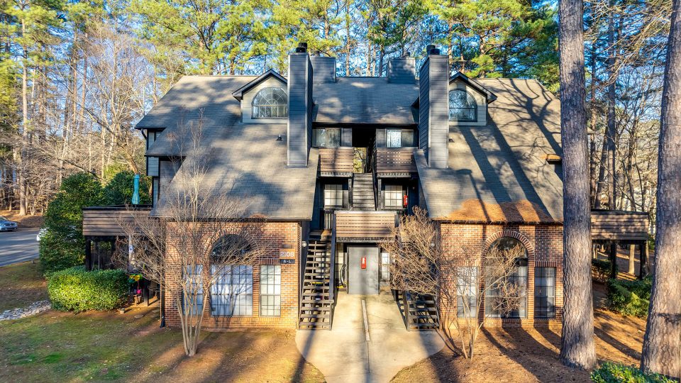 the apartment building is surrounded by trees and has a large front porch at The  Quinn on Ravenglass
