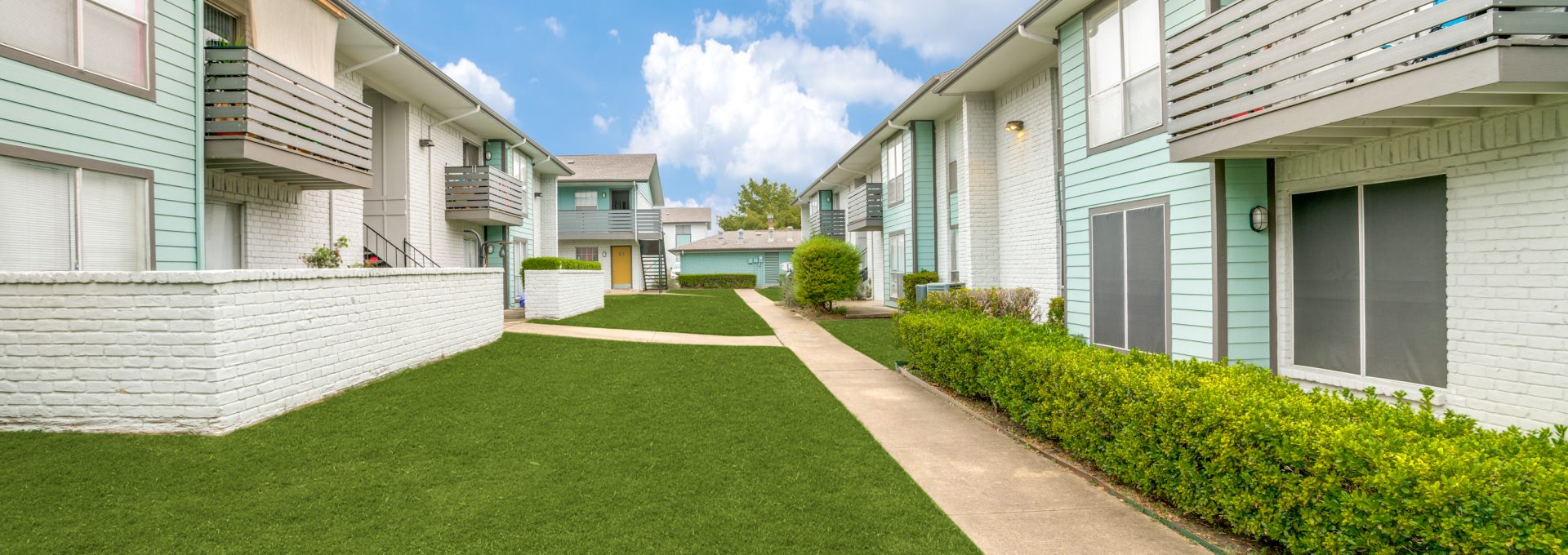apartment complex with lawn and grass in front at The Las Ventanas