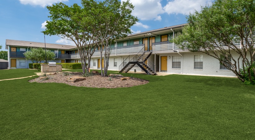 the exterior of an apartment complex with lawn and trees at The Las Ventanas