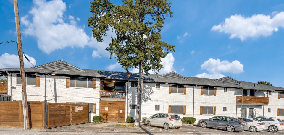 a large apartment building with cars parked in front at The  Rosedale