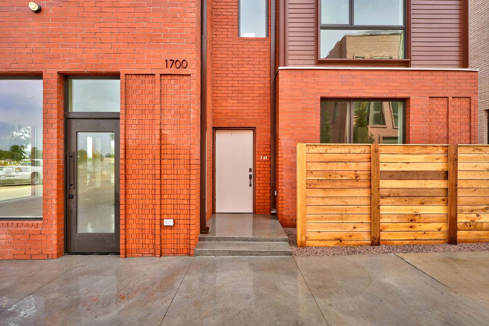a brick building with a wooden fence and a door at The Spoke Street Apartments