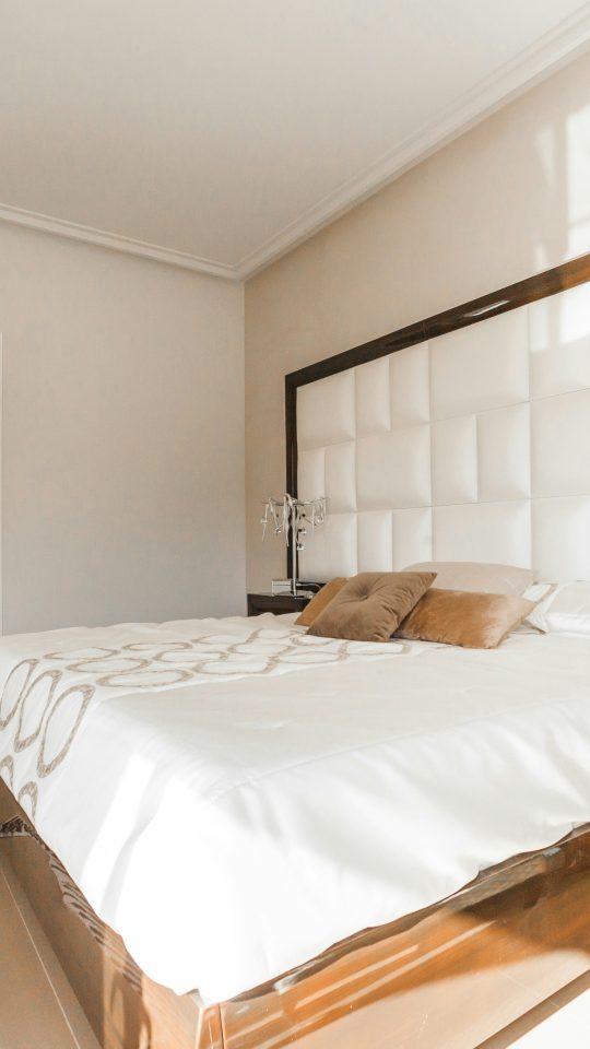brown wooden bed frame with white cover beside brown wooden nightstand