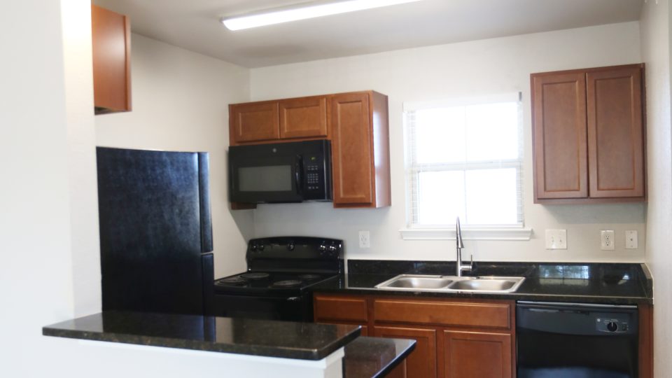 a kitchen with black appliances and wood cabinets at The Wilson Place 